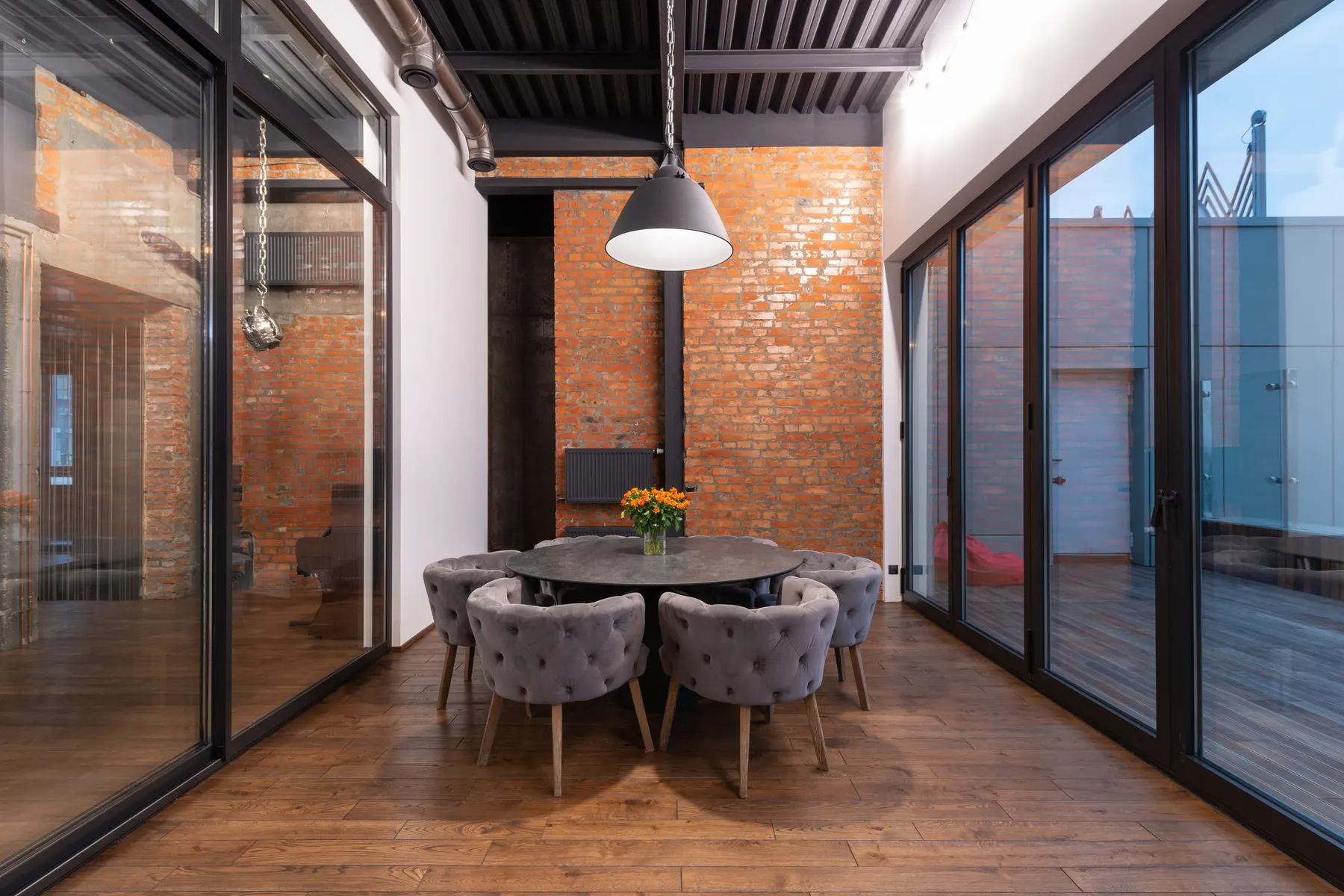 Comedor con dos frentes de vidrio de suelo a techo en perfil antracita, en un día nublado. El color oscuro es el más pedido en elevables, y en fachada muy soleada conviene saber que trabaja más: el perfil dilata y el herraje lo nota.