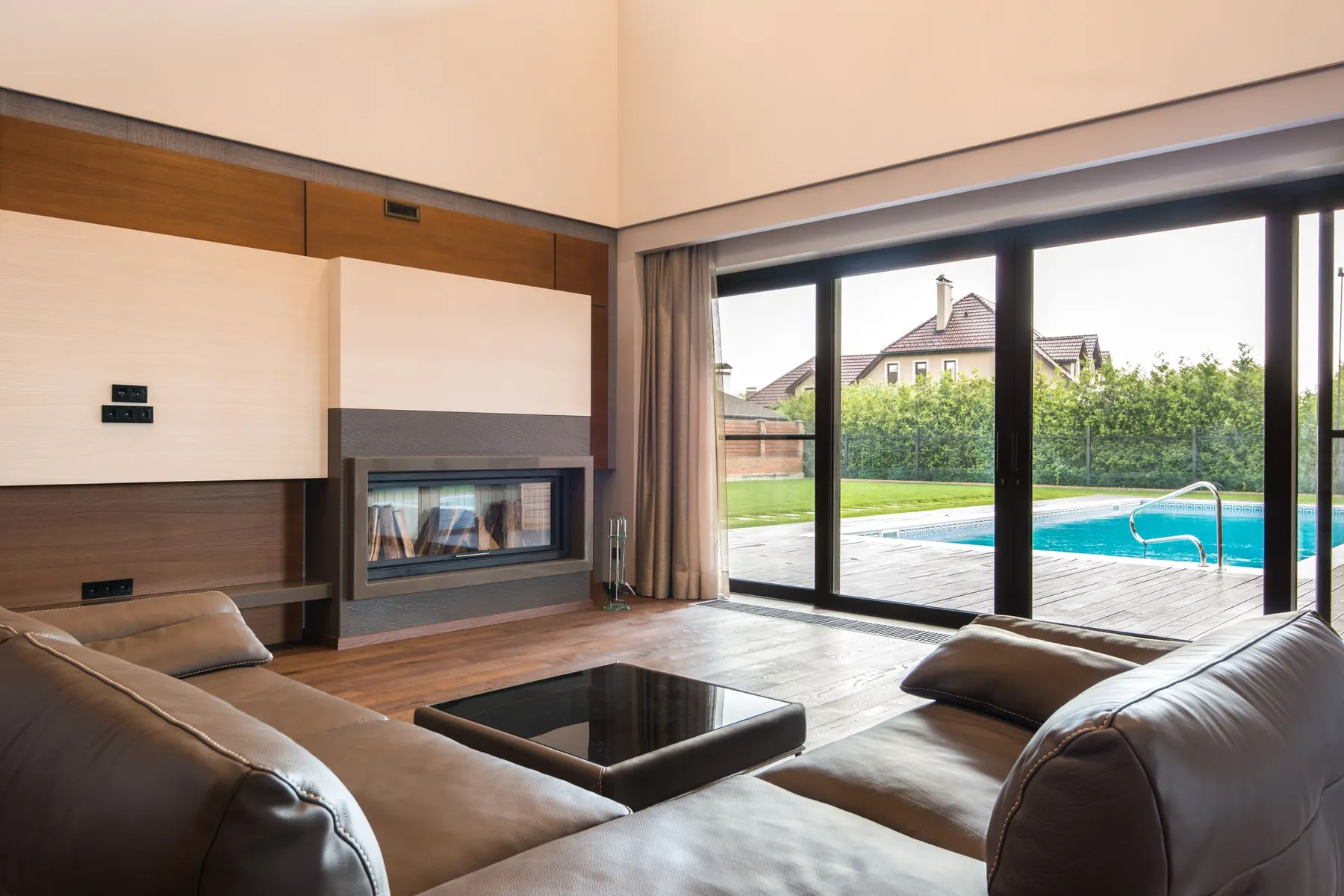 Salón con un frente de correderas de perfil oscuro que da a la terraza y a la piscina. Con varias hojas de suelo a techo, el paso abierto es una parte del frente: el resto sigue siendo vidrio.